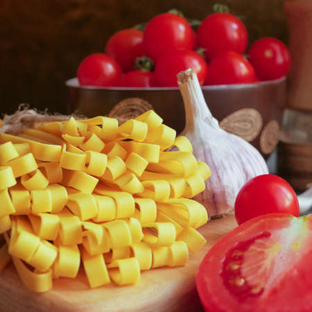 Tagliatelle close up with sliced ââtomato on a background of a plate with cherry tomatoesの写真素材