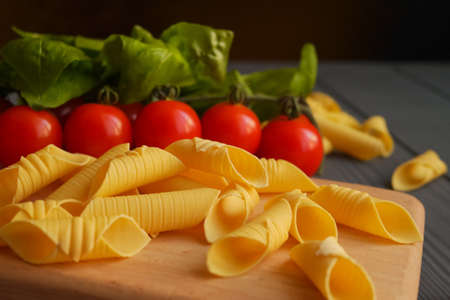 Garganelli pasta on a kitchen board in the background tomatoes and basilの写真素材