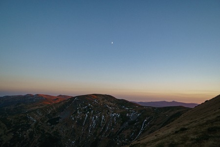 A little snow and moon above mountains sunset - landscape of the Ukrainian Carpathian Mountains, Chornohoraの写真素材