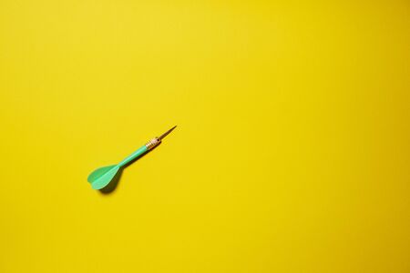 Single green arrow dart isolated on yellow backgroundの写真素材