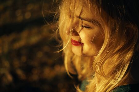 Autumn portrait of young happy smiling girl with red lips at sunsetの写真素材
