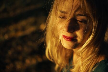 Autumn portrait of young girl with red lips at sunsetの写真素材