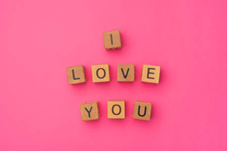 Wooden cubes with the phrase I Love You on an empty colorful pink background. Words of love are made of letters from wood for your girlfriend, boyfriend, wife, husband, for Valentine's Day greeting romantic postcard. Flat lay, top viewの写真素材