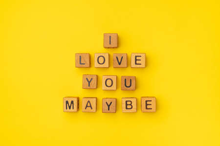 Wooden cubes with the phrase I Love You Maybe on an empty colorful yellow background. Words of love are made of letters from wood for your girlfriend, boyfriend, wife, husband, for Valentine's Day greeting romantic postcard. Flat lay, top viewの写真素材