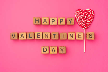 Wooden cubes with the phrase Happy Valentine's Day on an empty colorful pink background. Words of love are made of letters from wood for Valentine's Day and for your girlfriend, boyfriend, wife, husband greeting romantic postcard. Flat lay, top viewの写真素材