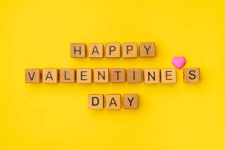 Wooden cubes with the phrase Happy Valentine's Day on an empty colorful yellow background. Words of love are made of letters from wood for Valentine's Day and for your girlfriend, boyfriend, wife, husband greeting romantic postcard. Flat lay, top viewの写真素材