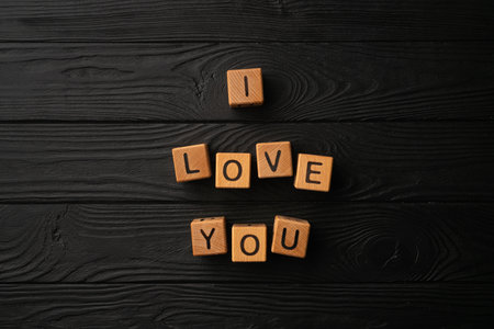 Wooden cubes with the phrase I Love You on a black background - a wooden table. Words of love are made of letters from wood for your girlfriend, boyfriend, wife, husband, for Valentine's Day greeting romantic postcard. Flat lay, top viewの写真素材