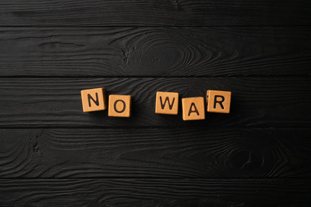 Wooden light yellow cubes with letters form the word War on a black wooden table. Flat lay, top view.の写真素材