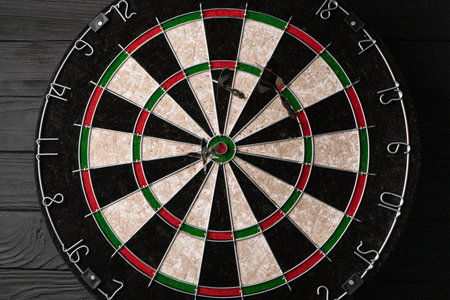 Three darts hit the dartboard. Lucky - one of the darts hits the bulls eye. The concept of winning and luckの写真素材
