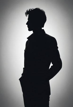 A man stands in silhouette, his profile sharply defined against a light backdrop, creating a striking contrast, evoking a sense of contemplation and tranquility.の素材