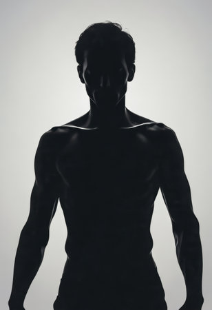 A man stands confidently in silhouette with a strong physique, set against a bright white backdrop, capturing a moment of strength and artistic simplicity.の素材