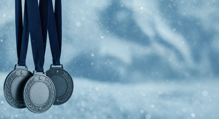 A trio of silver-toned recognition medals with blank centers and decorative borders are suspended against a softly blurred, snowy blue backdrop with shimmering bokeh effects.の素材