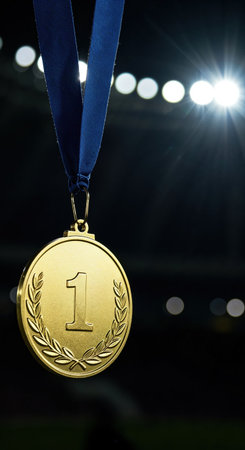 A prestigious first place gold medal with a textured blue ribbon is prominently displayed under bright stadium lights, creating a dramatic backdrop for success.の素材