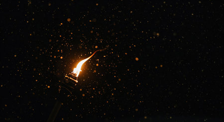 The warm glow of a burning torch illuminates a cascade of golden, luminous particles dancing in the deep black darkness, evoking a mysterious and enchanting nighttime atmosphere.の素材