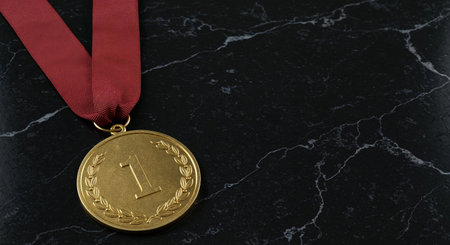 A prestigious first-place gold medal, adorned with a deep red ribbon, is prominently displayed against a luxurious black marble background with elegant white veining, symbolizing success and victory.の素材