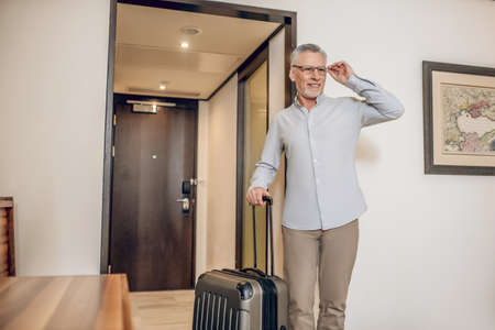 Gray-haired confident man in a hotel roomの写真素材