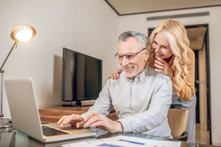 A man working from home, his wife standing next to himの写真素材