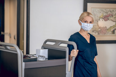 Service woman in a protective mask sholding bottles with waterの写真素材