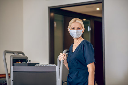 Service woman in a protective mask with a trolleyの写真素材