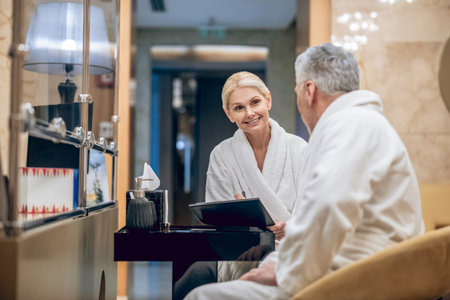 A man and a woman in a white robe sitting in a spa centerの写真素材