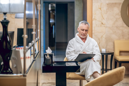 A man in a white robe sitting in a spa centerの写真素材