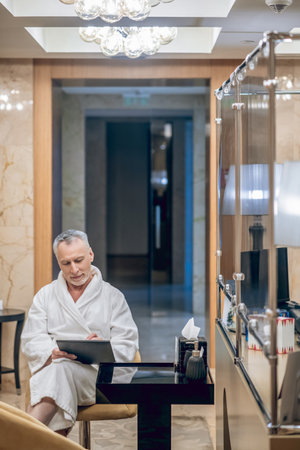A man in a white robe sitting in a spa centerの写真素材