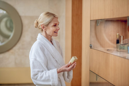 A womnain a white robe choosing facial cream in a beauty centerの写真素材