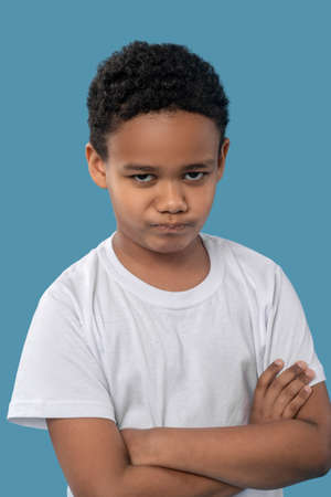 Angry dark skinned boy standing with folded hands