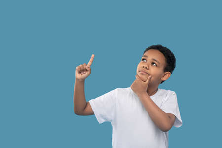 Pensive boy looking up pointing fingerの写真素材