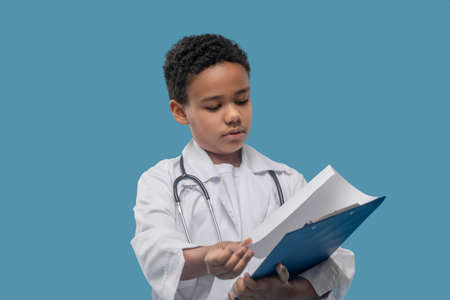 African american boy in lab coat with folderの写真素材