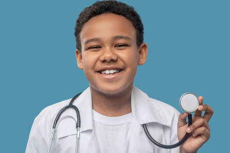 Happy dark skinned boy showing medical stethoscopeの写真素材