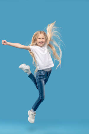Cheerful little girl jumping in photo studioの写真素材