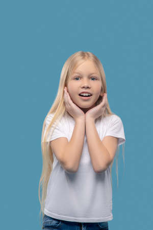 Little surprised girl with hands near faceの写真素材