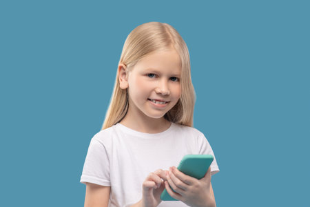 Cheerful girl with smartphone in her handsの写真素材