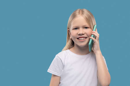 Cheerful girl in white tshirt communicating on smartphoneの写真素材