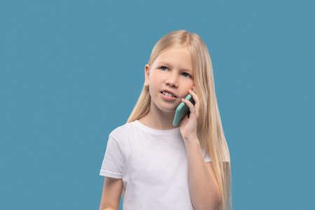 Serious long-haired girl talking on smartphoneの写真素材