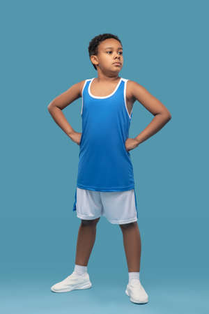 Darkskinned confident boy in sportswear on blue backgroundの写真素材