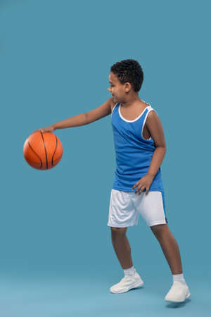 Boy in sportswear moving with ball in basketballの写真素材