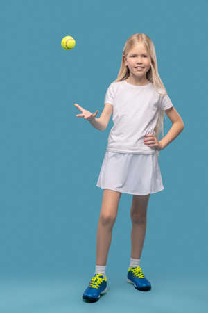 Girl standing tossing up tennis ballの写真素材
