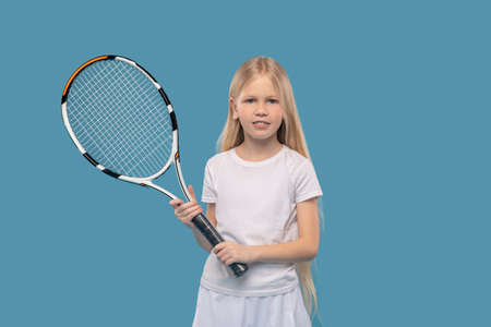 Happy primary school girl with tennis racketの写真素材