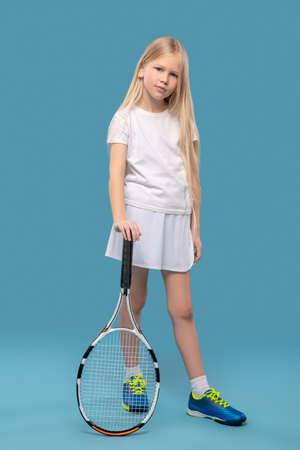 Girl standing leaning her hand on tennis racketの写真素材
