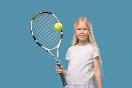 Happy teen tennis player hitting ball with racketの写真素材