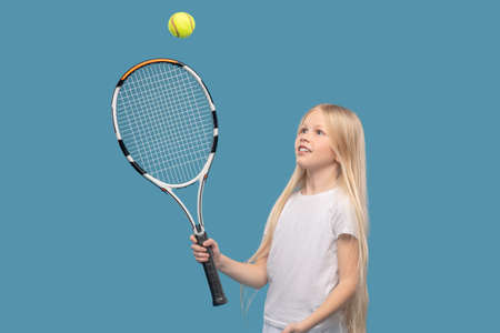 Girl hitting ball with tennis racketの写真素材