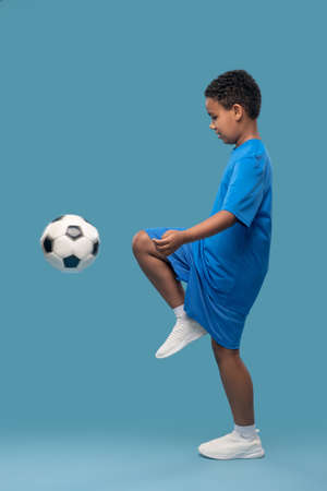 Profile of boy kneeing soccer ballの写真素材