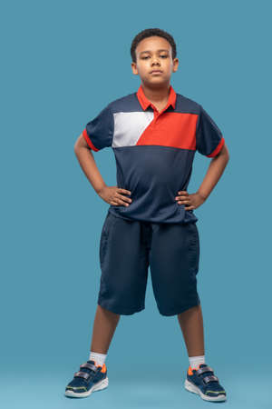 Dark skinned boy in sportswear on blue backgroundの写真素材