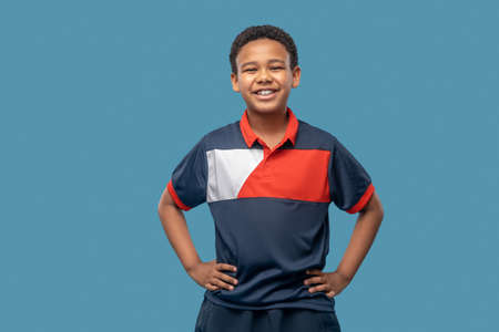 Smiling boy in sports tshirt hands on waistの写真素材