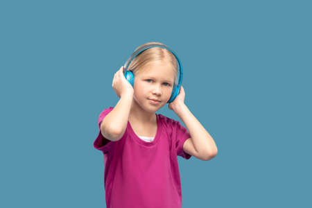 Cute blonde girl in blue headphonesの写真素材
