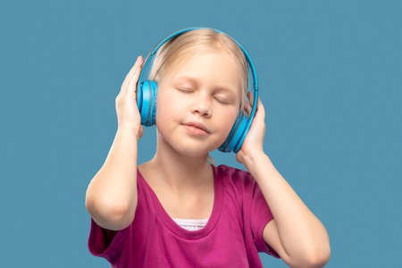 Primary school girl with closed eyes wearing headphonesの写真素材