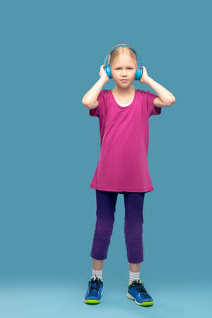 Girl in sportswear with headphones on blue backgroundの写真素材