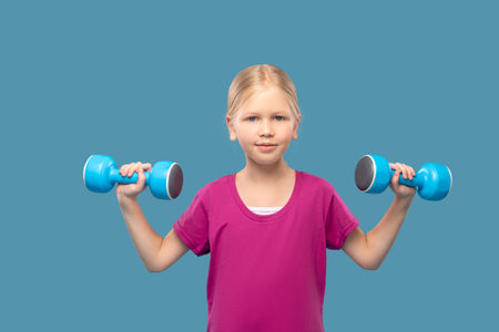 Blonde girl in sports tshirt with dumbbellsの写真素材